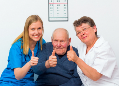 elderly man showing thumbs up with his caregivers