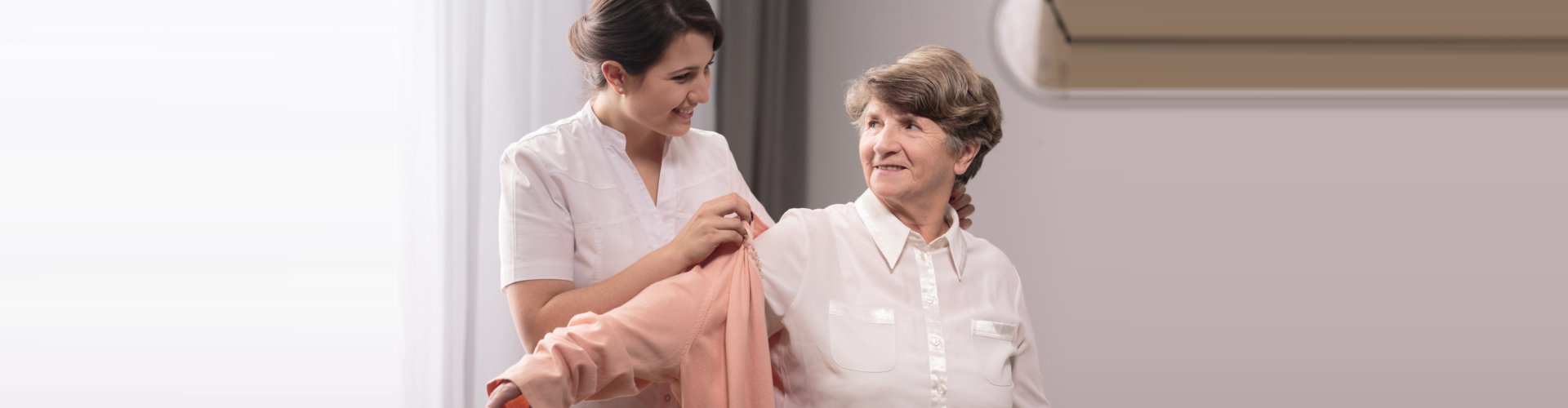 young lady dressing the senior woman